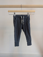 Dark grey children's jogger pants with drawstring, displayed on a wooden hanger.