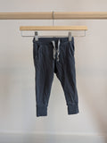 Dark grey children's jogger pants with drawstring, displayed on a wooden hanger.