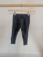 Dark grey children's jogger pants with drawstring, displayed on a wooden hanger.