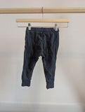 Dark grey children's jogger pants with drawstring, displayed on a wooden hanger.
